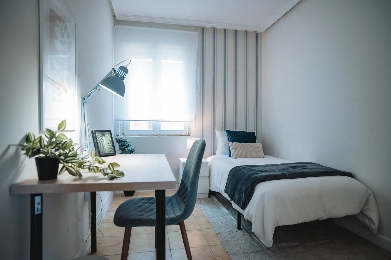 Habitación individual luminosa con escritorio y lámpara
